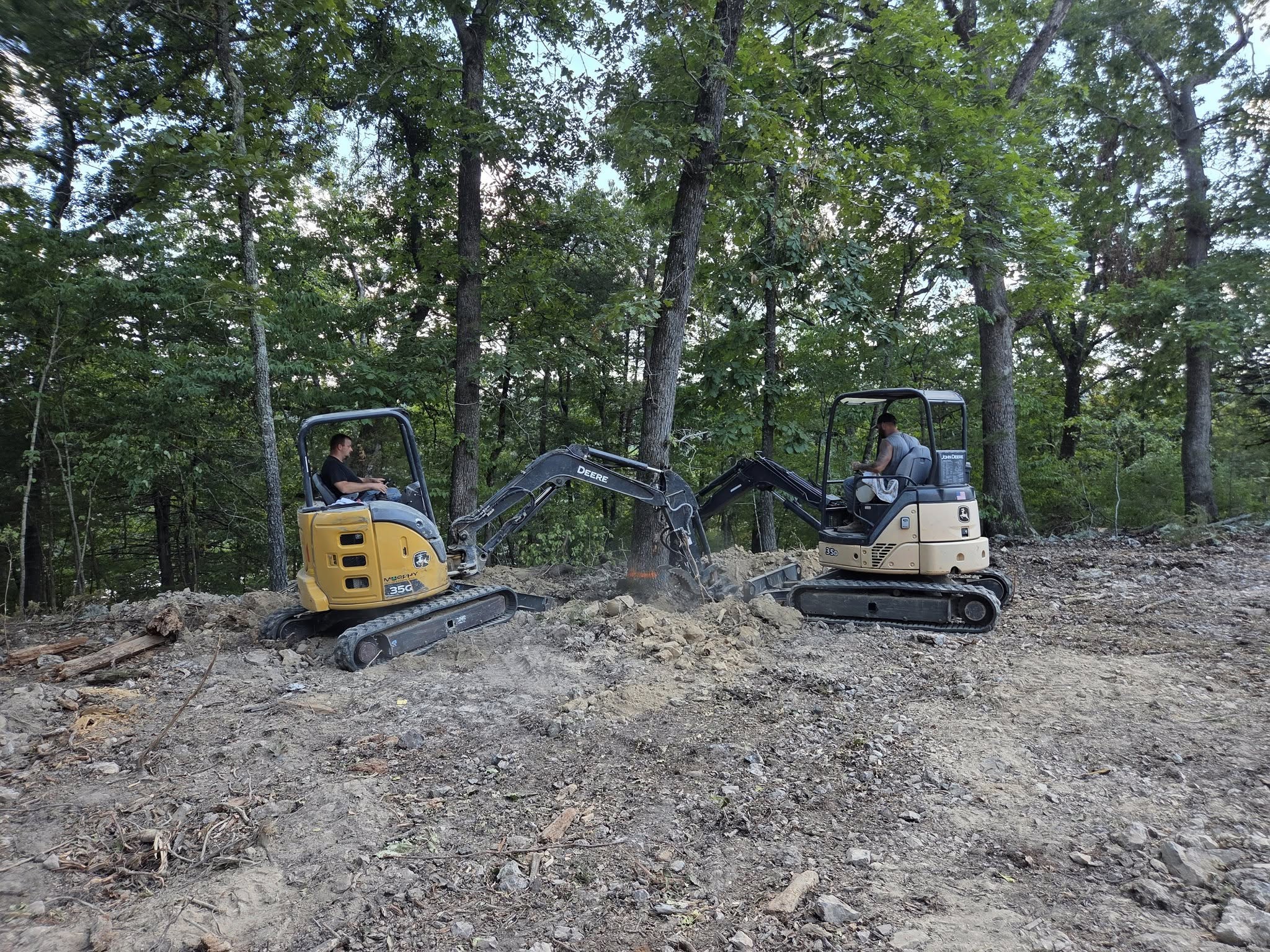 two excavators working to remove trees and clear a construction site