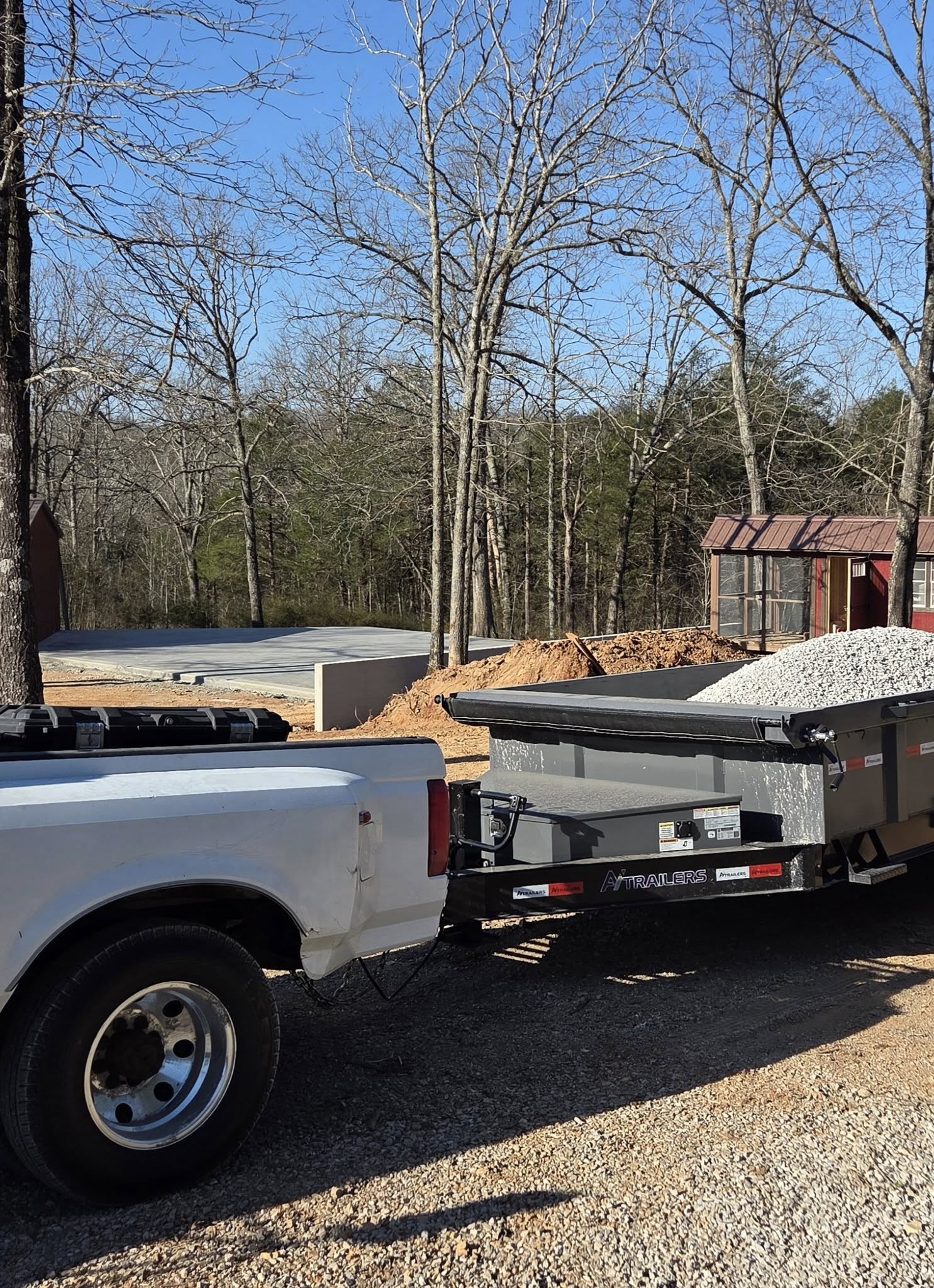 a truck and trailer loaded with gravel and a debris pile behind it